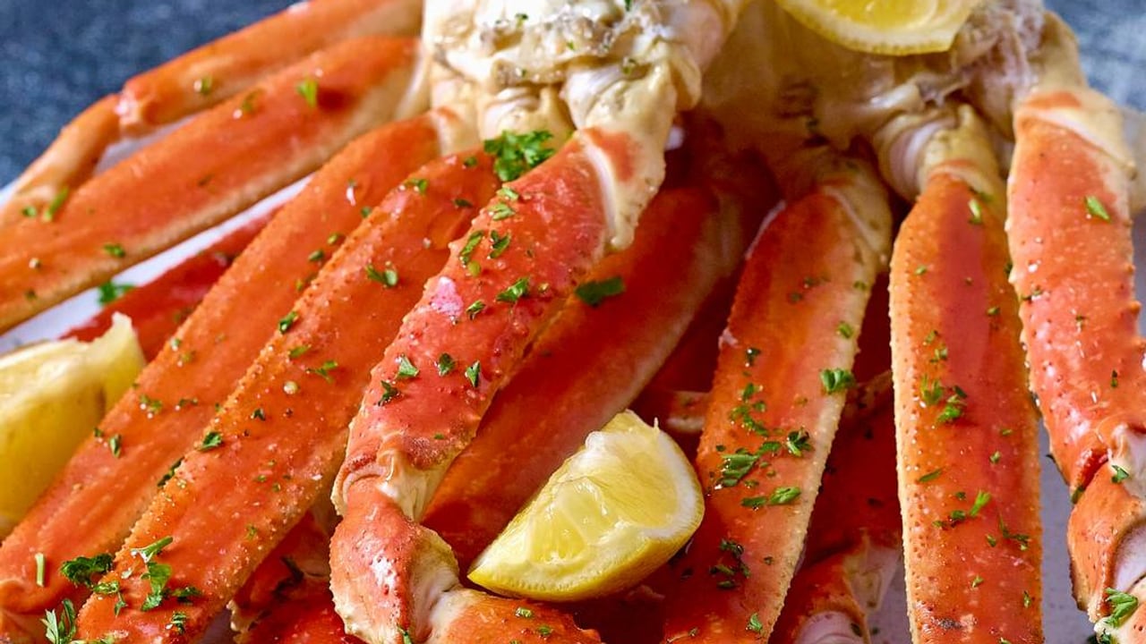 A plate of snow crab legs with lemon wedges and parsley